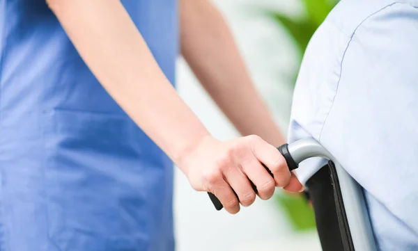 Krankenschwester schiebt Patienten in den Rollstuhl — Stockfoto