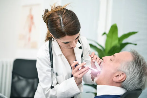 Doktor hasta ağzına bakıyor — Stok fotoğraf
