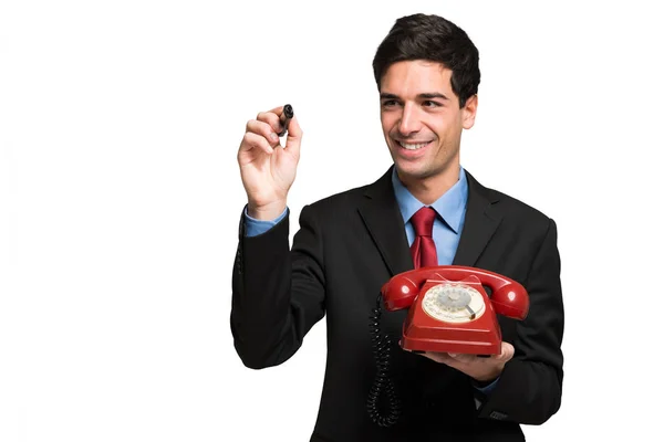 Empresário usando caneta enquanto segurando o telefone — Fotografia de Stock