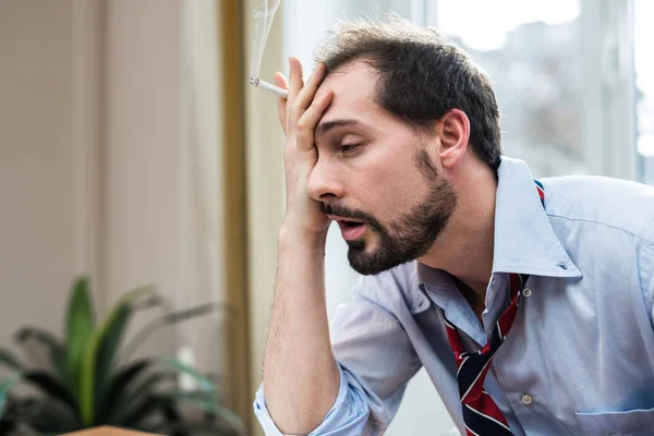 Шокированный бизнесмен курит сигарету — стоковое фото