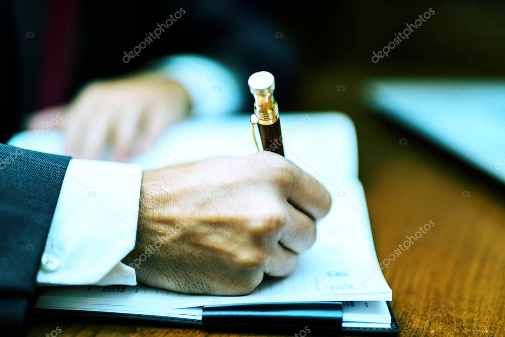 man writing on notebook