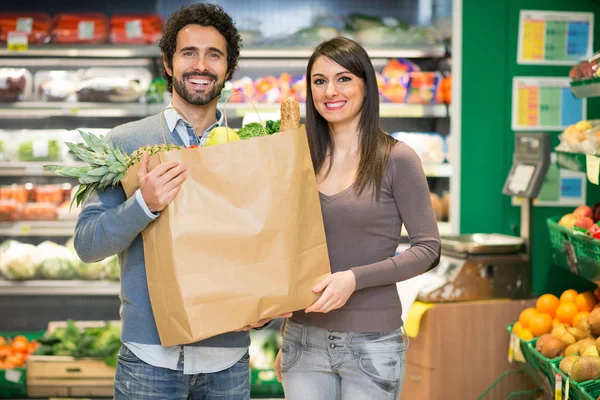 Couple holding bag full of food — Stock Photo, Image