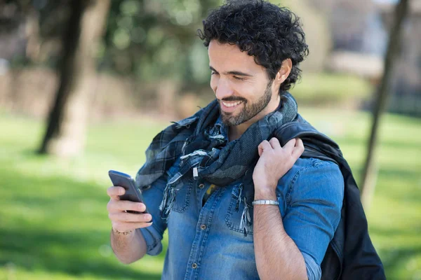 公園で携帯電話を使用している人 — ストック写真