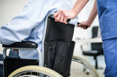 Bir hastanın tekerlekli sandalye iterek hemşire