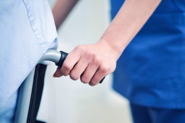 Bir hastanın tekerlekli sandalye iterek hemşire