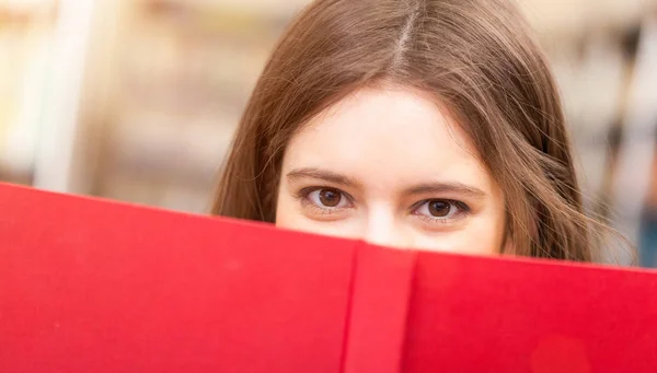 Student looking from behind book — Stock Photo, Image