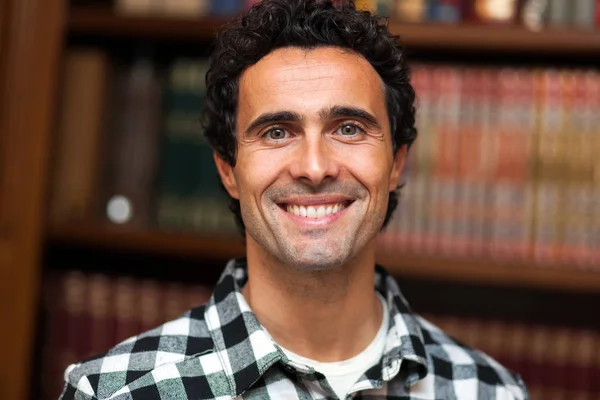 Homem sorrindo na biblioteca — Fotografia de Stock