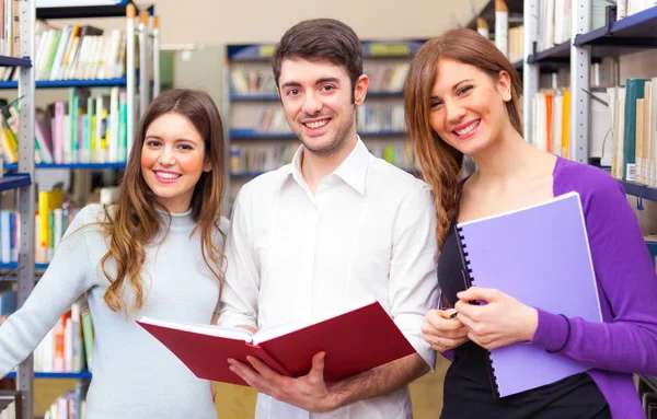 Lächelnde Studenten in der Universitätsbibliothek — Stockfoto