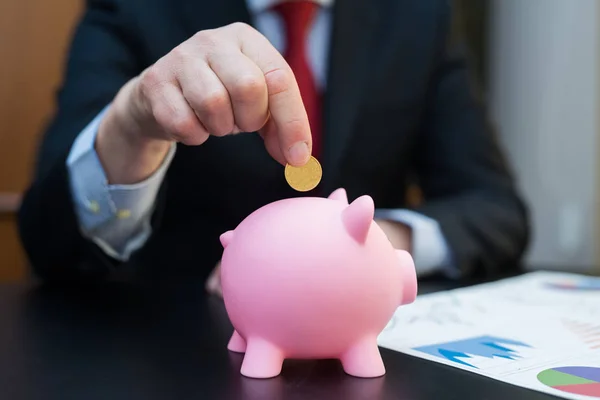 Zakenman geld aanbrengend piggy bank — Stockfoto