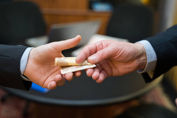 Человек берет взятку у другого.
