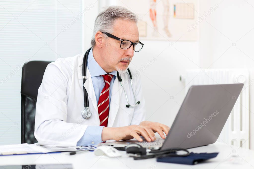 Senior doctor working at laptop