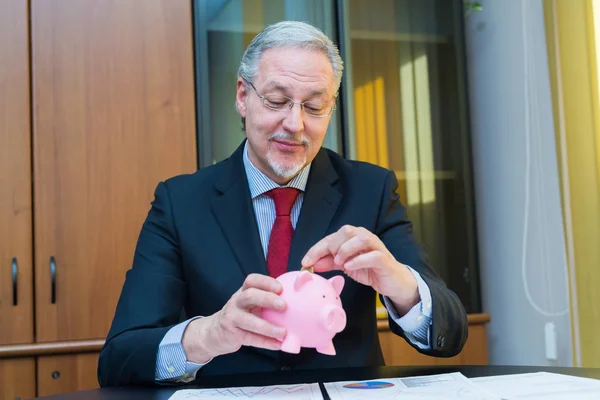 Geschäftsmann legt Geld in Sparschwein — Stockfoto