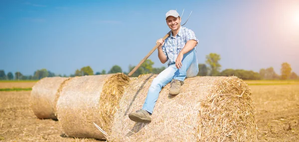 Rolnik siedzący na belę siana w dziedzinie — Zdjęcie stockowe