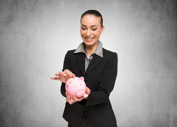 Frau legt Geld in ihr Sparschwein — Stockfoto