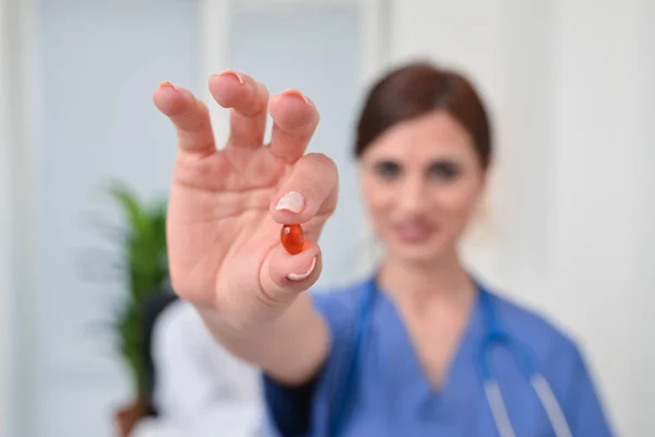 Усміхнена медсестра тримає таблетку — стокове фото