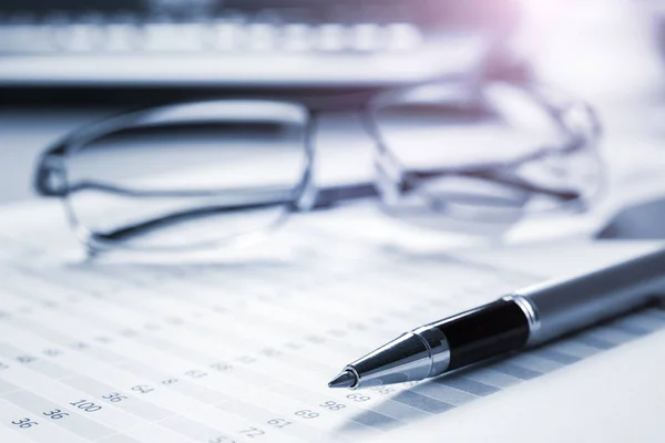 Pen and eyeglasses on financial documents — Stock Photo, Image