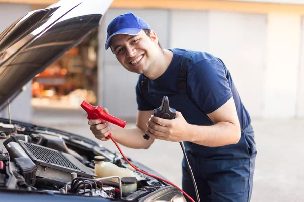 Monteur gebruik van kabels voor het starten van de motor van een auto — Stockfoto