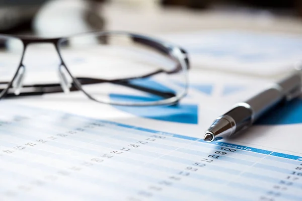 Pen and eyeglasses on financial documents — Stock Photo, Image