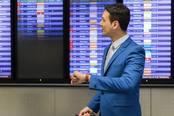 Guapo hombre de negocios comprobar el tiempo en aeropuerto — Foto de Stock