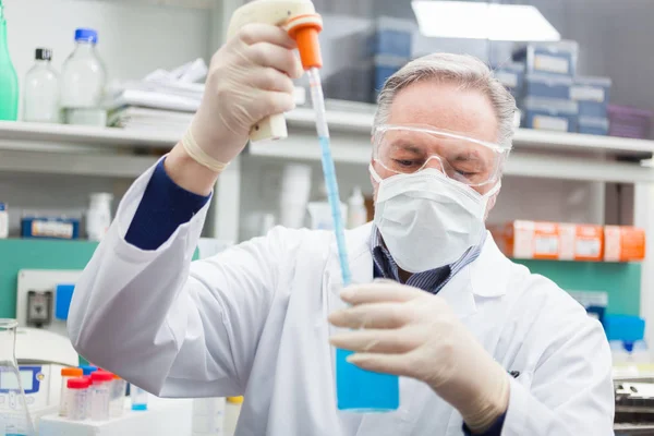 Wetenschapper vullen een kolf in laboratorium — Stockfoto