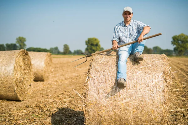 Фермер сидит на тюке сена — стоковое фото