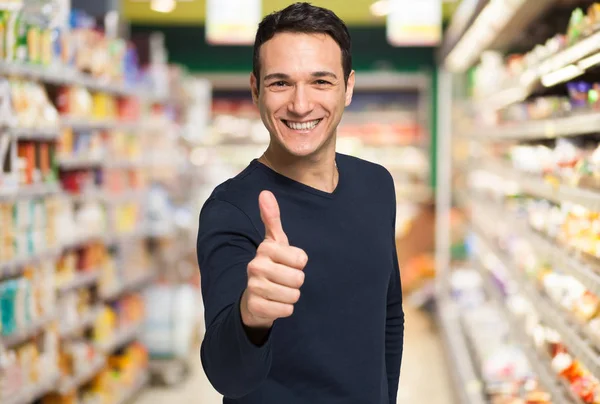 Homme montrant pouces au supermarché — Photo