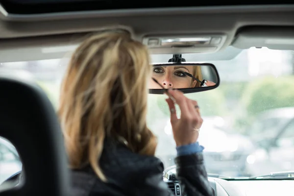 Woman applying make-up in car — Stock Photo, Image