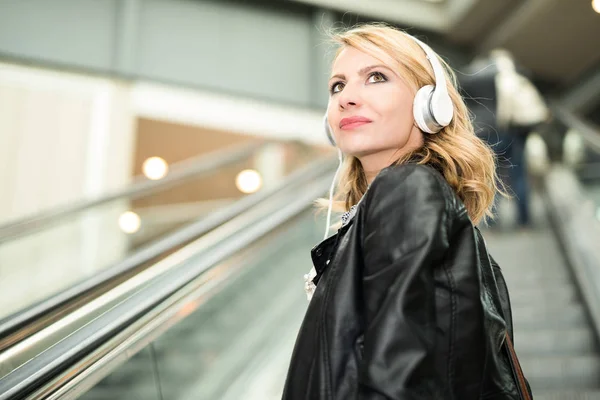 Mulher na escada rolante ouvir música — Fotografia de Stock