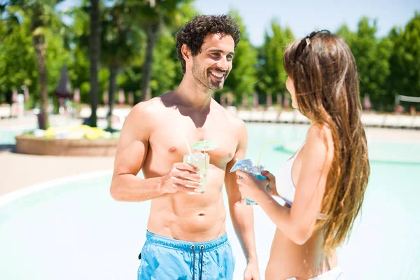夫妻二人在游泳池边喝鸡尾酒 — 图库照片