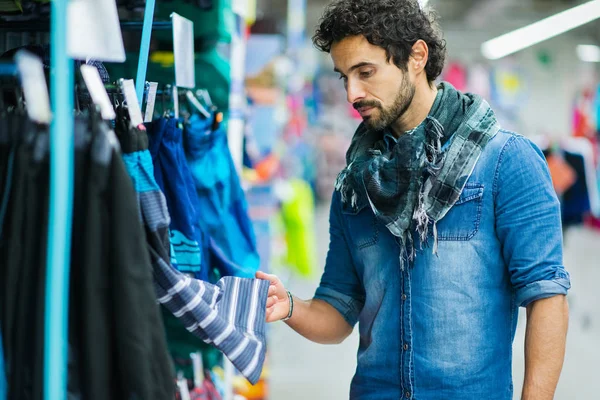 Мужчина ищет одежду в магазине — стоковое фото