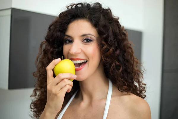 Woman eating a yellow apple — Stockfoto