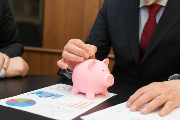 Empresário colocando dinheiro em banco porquinho — Fotografia de Stock