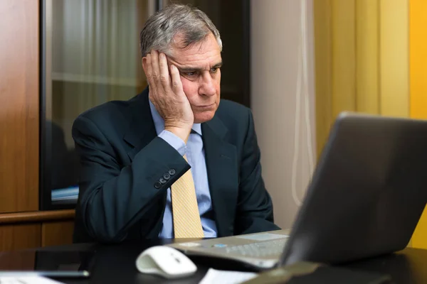 Uttråkad affärsman tittar på laptop — Stockfoto