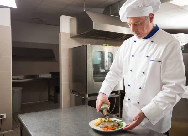 Chef-kok olijfolie over het vlees gieten — Stockfoto