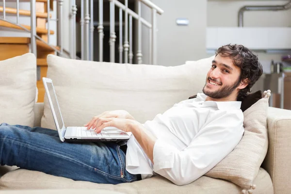 Man using his computer on couch — Stock Photo, Image