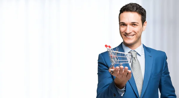 Businessman holding mini shopping cart — Stock Photo, Image