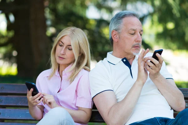 Пара, которая смотрит на свои мобильные телефоны — стоковое фото