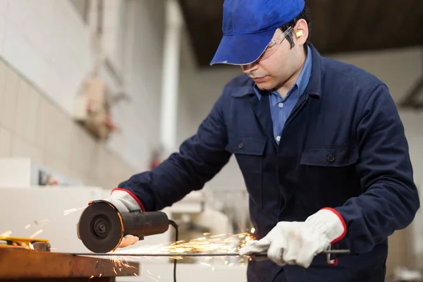 Trabajador que usa una amoladora en una fábrica —  Fotos de Stock