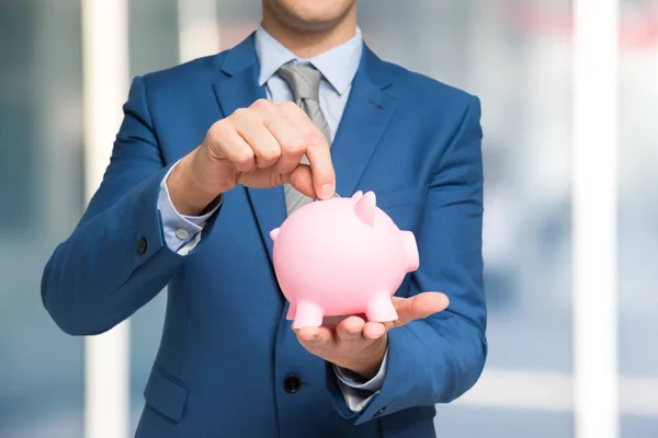 Man putting money in piggy bank — Stock Photo, Image
