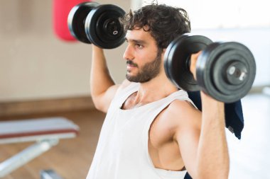 Vücut geliştirmeci dumbbells bir jimnastik salonu kaldırma