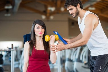Kişisel bir eğitmen denetimindeki bir spor salonunda çalışan kadın