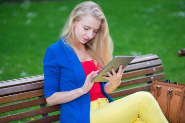 Bir parkta otururken bir tablet tutan kadın