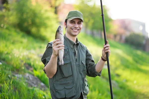 Fisherman holding a fishing pole and a trout