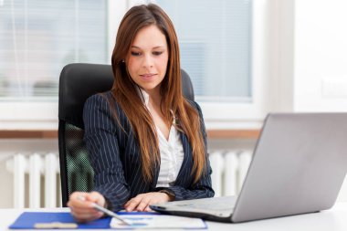 Dizüstü bilgisayar kullanarak ofiste çalışan iş kadını portresi