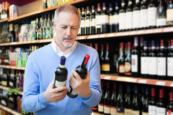 Человек Супермаркете Выбирает Правильное Вино — стоковое фото