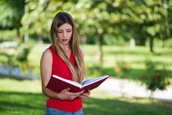 Портрет Молодой Блондинки Читающей Красную Книгу Парке Весной — стоковое фото