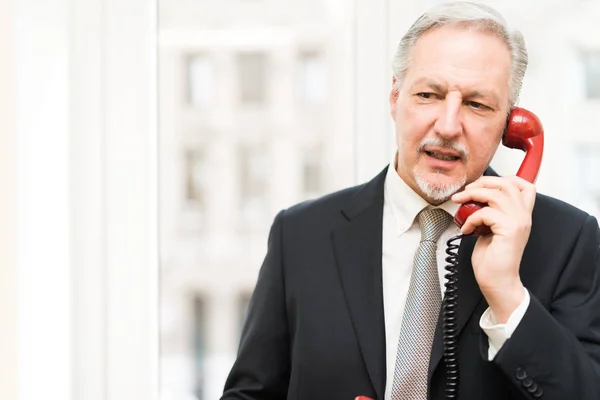 Businessman talking on a vintage phone in his office