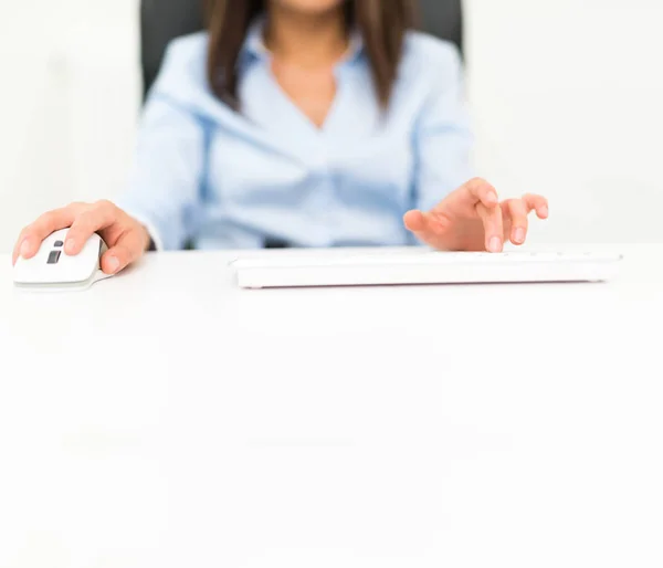 Detail of a person using a computer. Shallow depth of field, large copy-space on the white desk