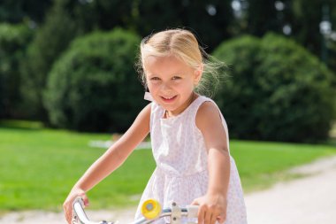 Mutlu kız parkta bisiklet kullanmayı öğrenmek bisikleti