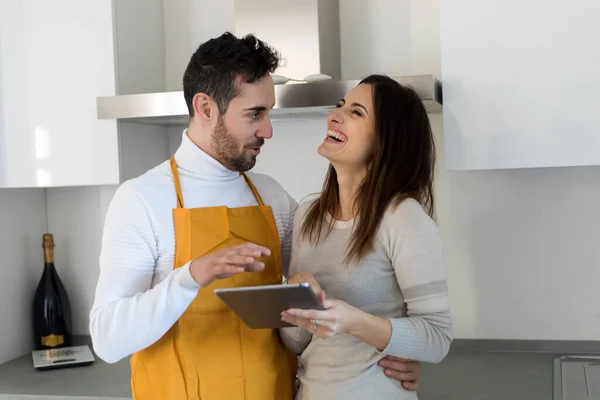 Couple ready to cook choosing a recipe with a digital tablet